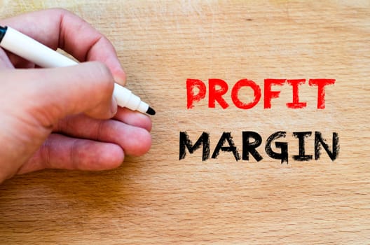 Human hand over wooden background and profit margin text concept