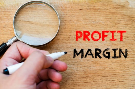 Human hand over wooden background and profit margin text concept