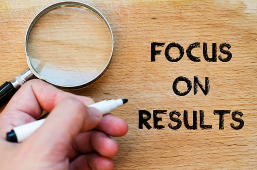 Human hand over wooden background and focus on results text concept