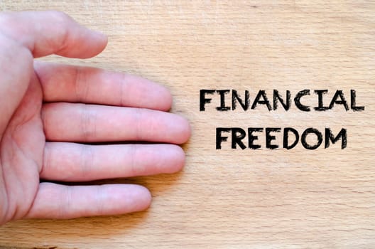 Human hand over wooden background and financial freedom text concept