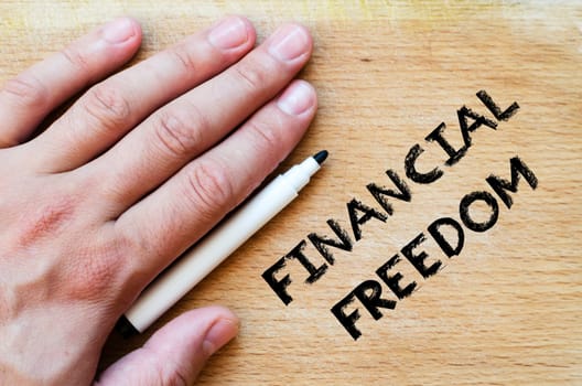 Human hand over wooden background and financial freedom text concept