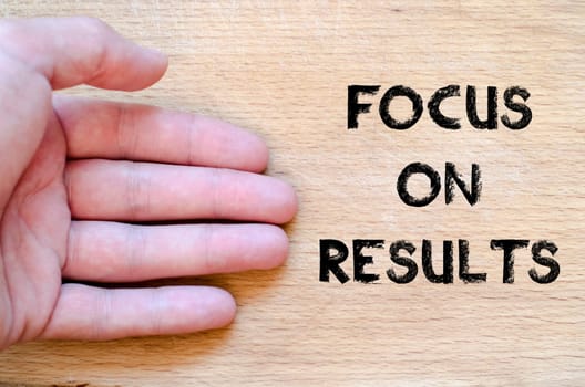 Human hand over wooden background and focus on results text concept