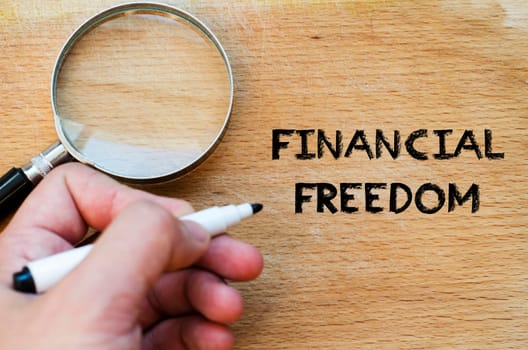 Human hand over wooden background and financial freedom text concept