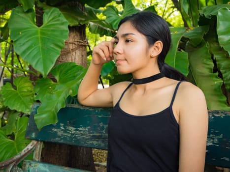 Asian woman sitting on the wooden chair in the garden
