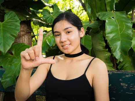 Asian woman sitting on the wooden chair in the garden