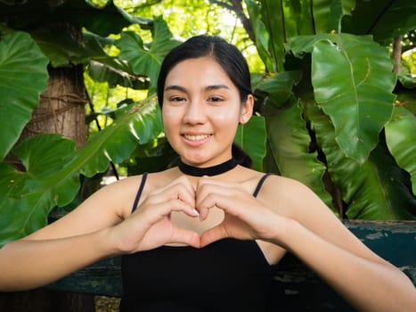 Asian woman sitting on the wooden chair in the garden