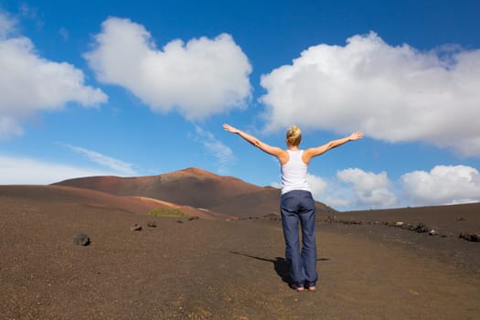Woman hiking in nature can see the peak of Timanfaya volcano, nearly made it to top.