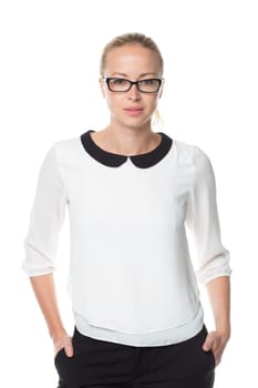Portrait of beautiful smart young businesswoman wearin black eyeglasses, standing with arms in pockets against white background.