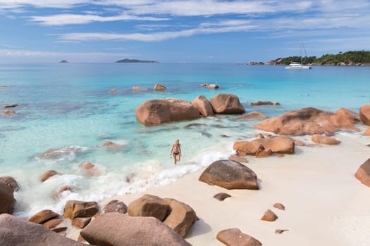 Woman wearing stylish bikini enjoying swimming and snorkeling at amazing Anse Lazio beach on Praslin Island, Seychelles. Summer vacations on picture perfect tropical beach concept.