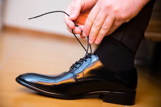 Groom putting his wedding shoes. Hands closeup.