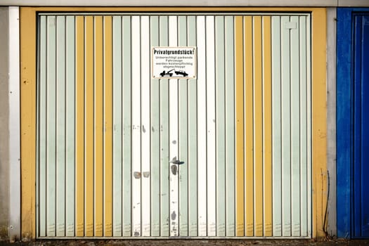 A striking garage door made of tin strips and washed-out paint.