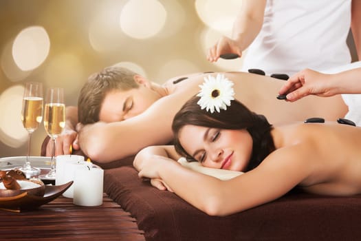 Close-up Of A Relaxed Young Couple Receiving Hot Stone Therapy At Beauty Spa