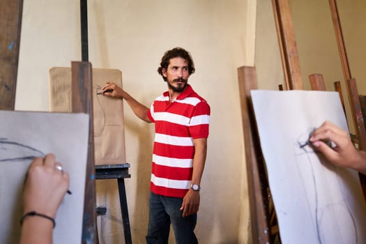 School of art, college of arts, education for group of young students. Portraif of happy hispanic professor smiling, man working as teacher.