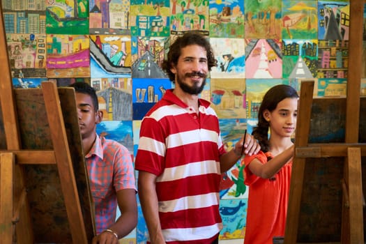 School of art, college of arts, education for group of young students. Portraif of happy latino professor smiling, man working as teacher and looking at camera.