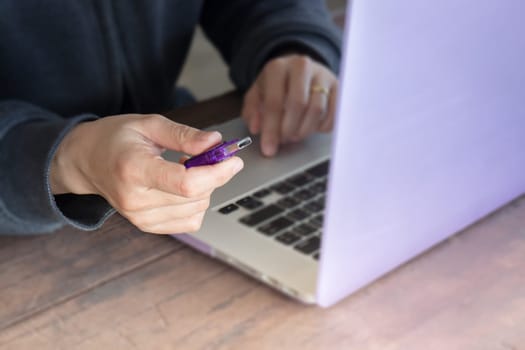 Woman using flash drive and laptop, stock photo