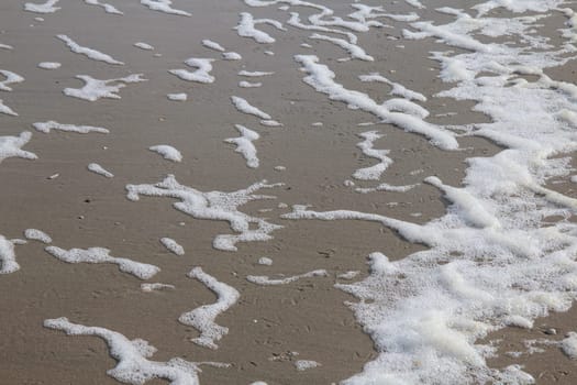Waves with white foam crowns flood the sandy beach.