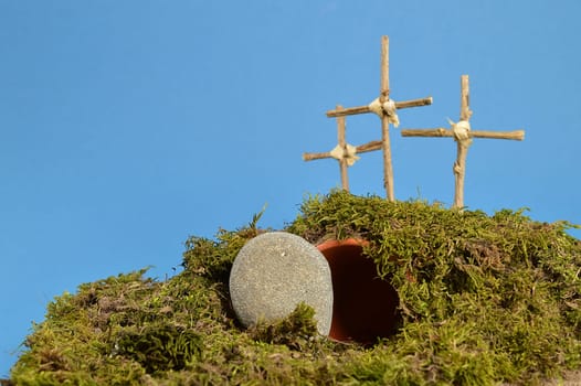 resurrection garden as easter decoration with a stone near the empty tomb and three crosses on a hill above