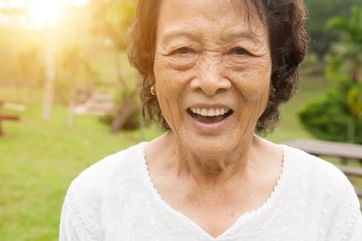 Portrait of healthy happy Asian senior woman laughing at outdoor nature park, morning beautiful sunlight background.