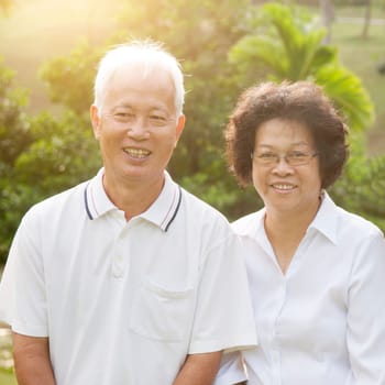 Portrait of healthy Asian seniors retiree couple having good time at outdoor nature park, morning beautiful sunlight background.