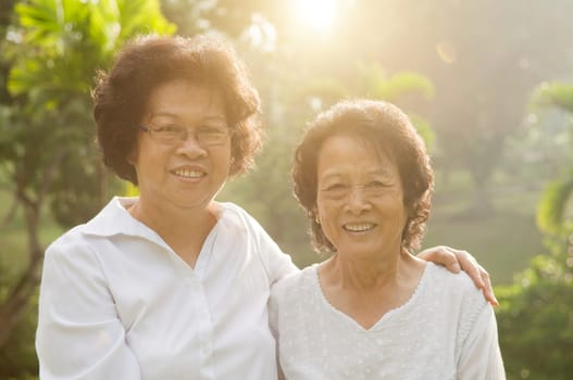 Portrait of healthy Asian seniors mother and daughter smiling at outdoor nature park, morning beautiful sunlight background.