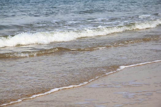 Waves with white foam crowns roll over the surface of the sea.
