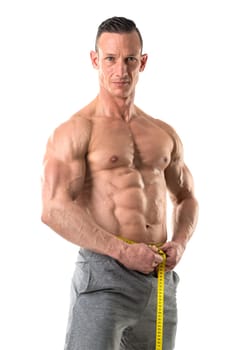 Athletic man with great phisique, measuring his waist isolated in white