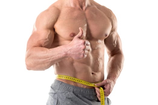 Athletic man with great phisique, measuring his waist isolated in white