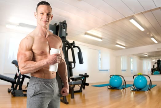 Powerful athletic man with great physique holding a gym bottle