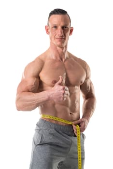 Athletic man with great phisique, measuring his waist isolated in white