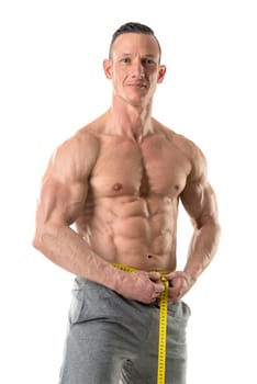 Athletic man with great phisique, measuring his waist isolated in white