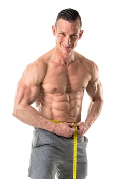 Athletic man with great phisique, measuring his waist isolated in white
