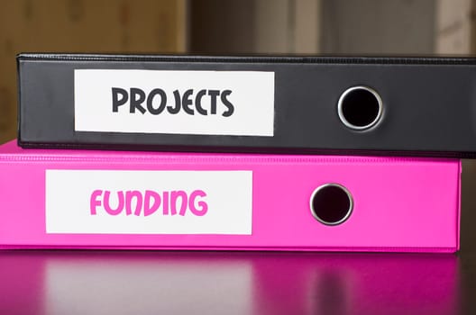 Bright office folders over dark background and projects and funding text concept