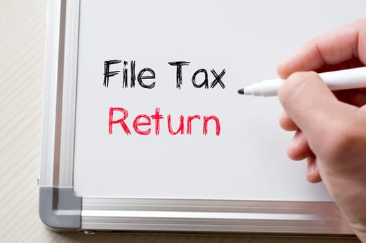 Human hand writing file tax return on whiteboard