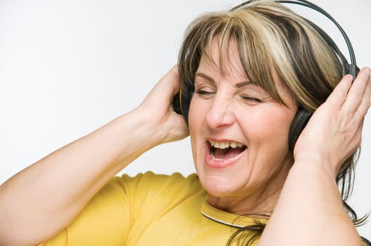 Head-and-shoulder view of a middle-aged woman with closed eyes and headphones against a white background.