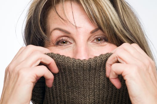 Frontal close up of a middle-aged woman with a turtlenut pulled over her nose