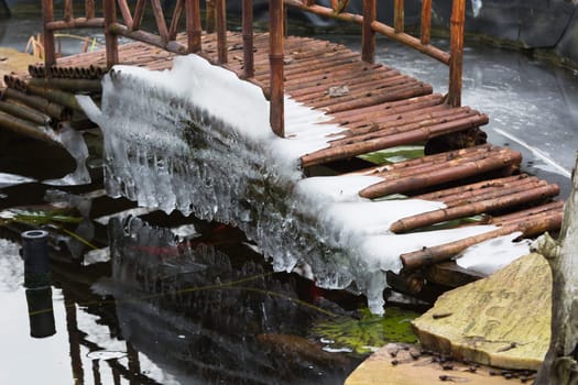 Icicles hang from a bridge over a frozen lake.