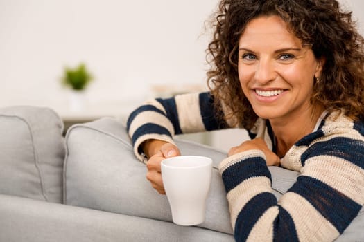Beautiful woman sitting on the sofa and drinking a coffee