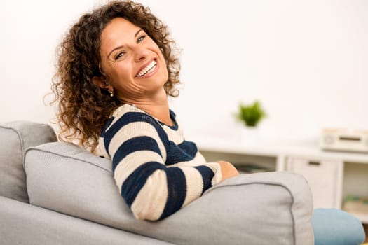 Beautiful happy woman at home sitting on the sofa