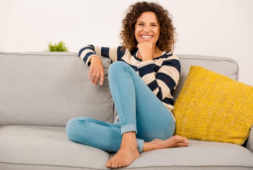 Beautiful happy woman at home sitting on the sofa