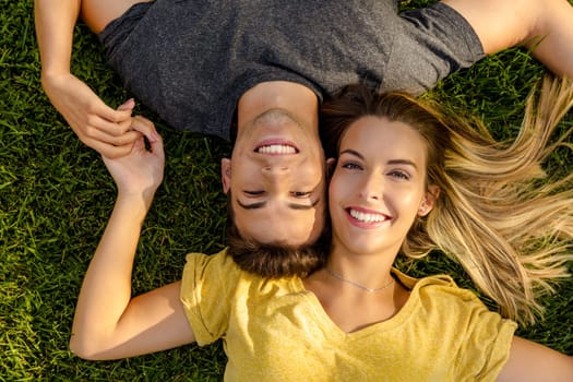 Portrait of a young beautiful couple lying on the grass