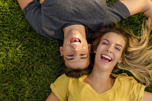 Portrait of a young beautiful couple lying on the grass