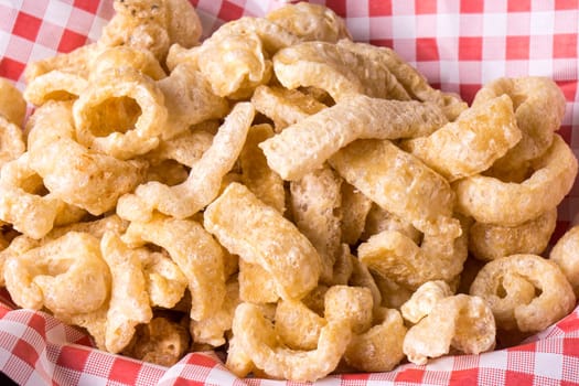 Delicious crispy pork rinds. A crisp salty snack on black glossy background