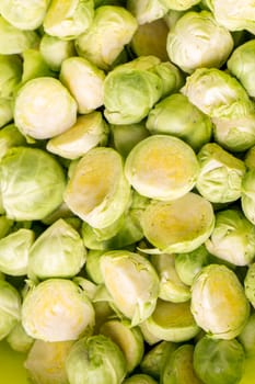 green fresh whole and cut organic Brussels sprouts, isolated on black glossy background