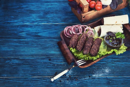 Grilled lula kebab - meat dish, with vegetable on a blue wooden background