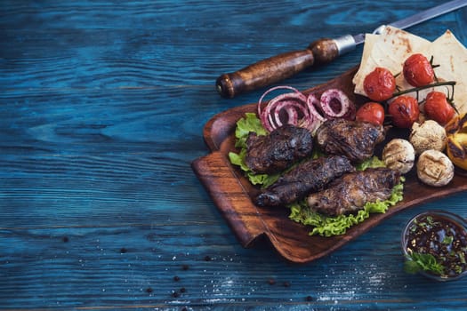 Grilled lamb meat with vegetable on a blue wooden background