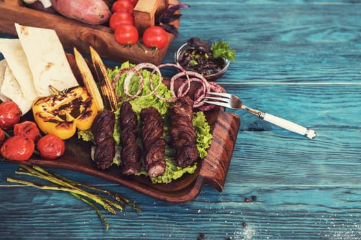 Grilled lamb meat with vegetable on a blue wooden background