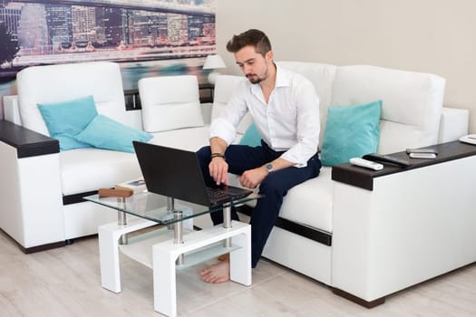 Surprised shocked man with opened mouth work at home with laptop