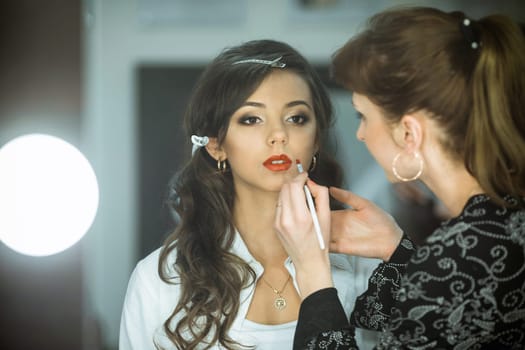 Professional master,makeup artist does cute,fashion,creative make-up,makes up eyes,lips.Beautiful,fashionable,glamorous,famous,nice,attractive,pretty,sexy celebrity,model,lady,girl,woman prepare for shooting.Nice face,pure,clean skin.Cosmetics.Salon