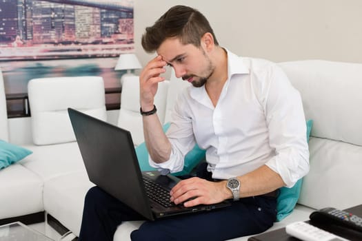 Thinking man in white shirt work at laptop