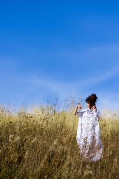 Beautiful,attractive,fashionable,gorgeous,pretty,nice girl in white dress in sunny,golden,yellow field with flowers,wheat,ears of wheat and blue sky.Amazing view.Beautiful nature.Posing girl in field.Beautiful, attractive, pretty, stunning heroine.